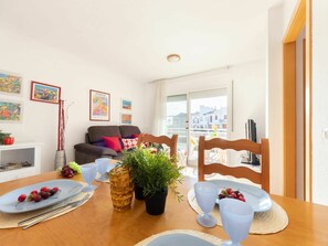 Een eetgedeelte met een houten tafel gedekt voor twee personen, een bank en een balkon met uitzicht.