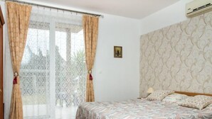 Een slaapkamer met een bed, gordijnen, een raam, een behang met patroon en een klein prentje.
