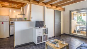 A modern kitchen with wooden beams, a built-in TV, and a sliding door leading to a balcony. - La Gaillarde by Interhome (Les Issambres)