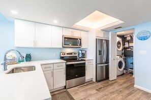 A modern kitchen with white cabinets, stainless steel appliances, and a built-in oven.