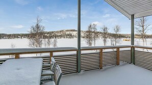 A covered outdoor seating area with a view of a snowy landscape and a lake. - Hallan karhu c, paritalo by Interhome (Hyrynsalmi)