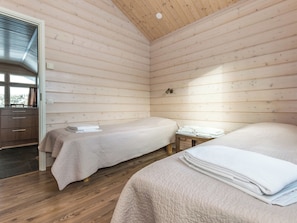 Een blokhut met twee bedden, een houten vloer en een raam.