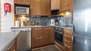 Uma cozinha moderna com armários de madeira, eletrodomésticos de aço inoxidável e painel de backsplash de pedra.