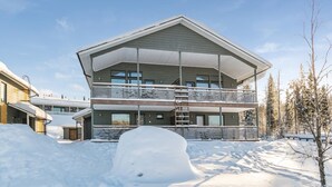 A modern two-story building with a covered balcony and a snow-covered ground. - Hallan karhu c, paritalo by Interhome (Hyrynsalmi)