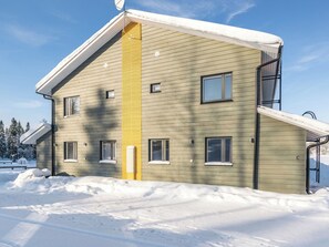 A two-story building with a sloped roof, multiple windows, and a snow-covered ground.