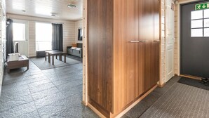 A hotel room with a wooden wardrobe, a sofa, a table, and a window. - Hallan karhu c, paritalo by Interhome (Hyrynsalmi)