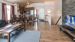 A spacious living area with wooden floors, a dining table, and a television. - Hallan karhu c, paritalo by Interhome (Hyrynsalmi)