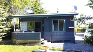 A small cabin with a covered porch, a satellite dish, and a gravel driveway. - Cosy cabin (Lumsden)