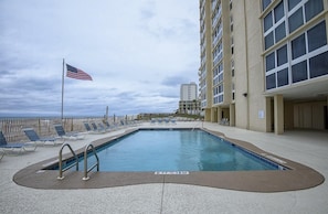 Relax by the rectangular pool surrounded by lounge chairs and a flagpole.