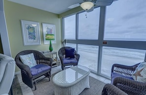 Relax in this beachside retreat with a view, featuring wicker furniture and artwork.