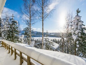 A snowy landscape with a wooden deck and snow-covered trees.