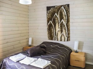A room with a bed, two bedside tables, and a wall-mounted tapestry. - Uulanlinna b, paritalo by Interhome (Hyrynsalmi)