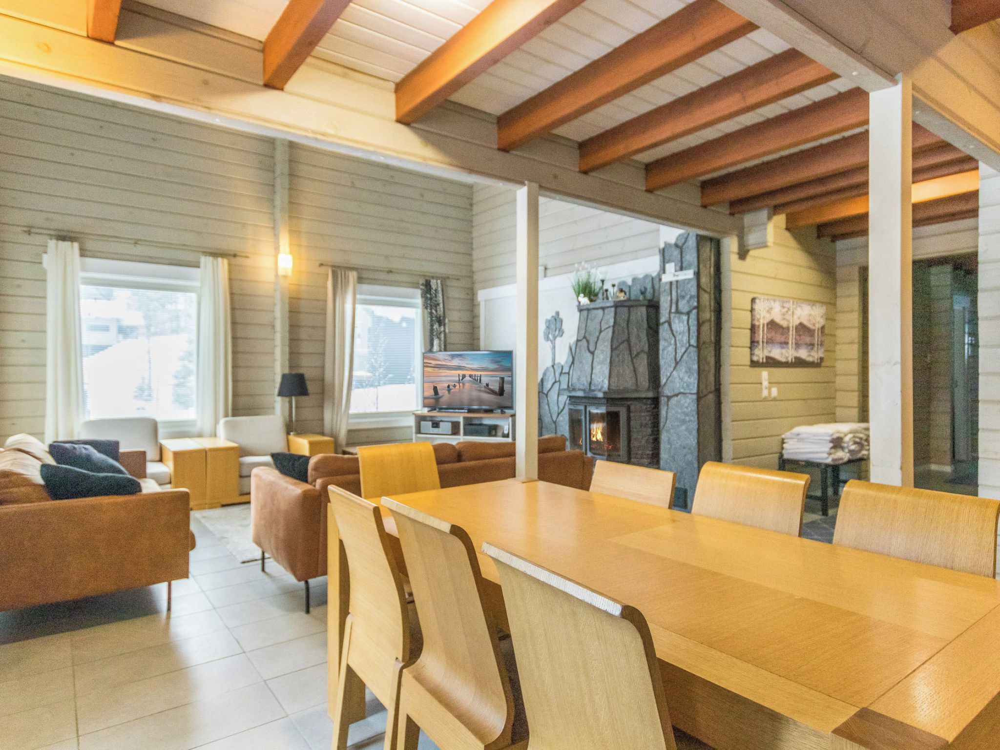 A spacious living area with a large wooden dining table, comfortable seating, a fireplace, and a television.