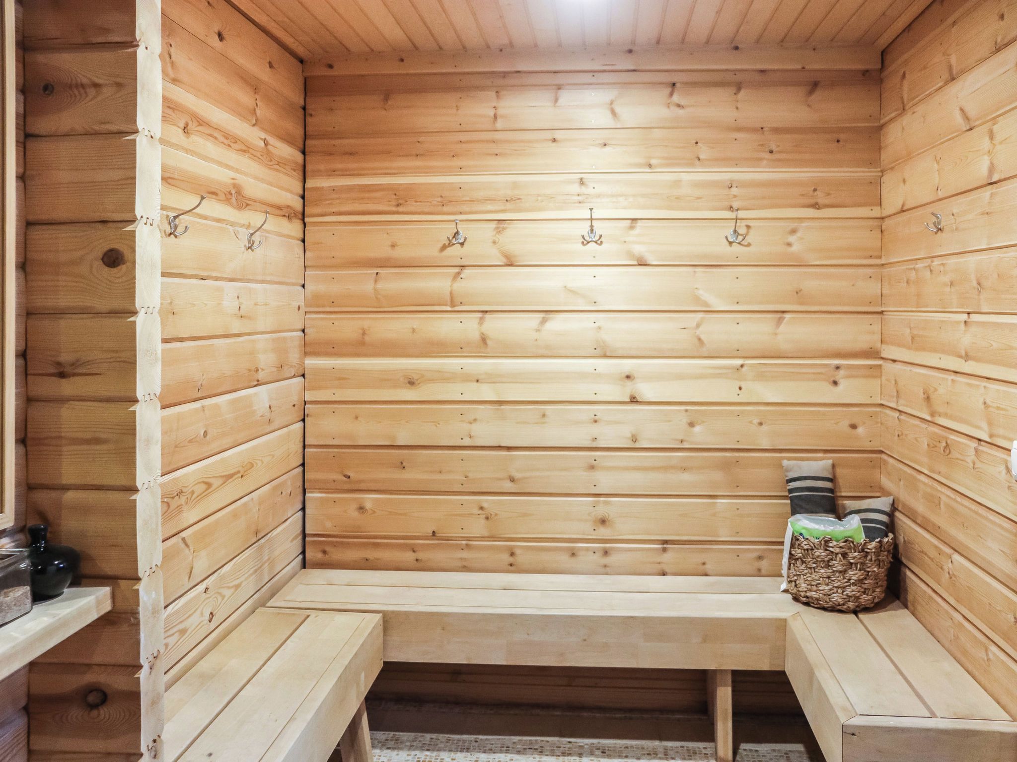 Puisesta laudeseinästä ja pyyhekoukuista varustettu sauna.