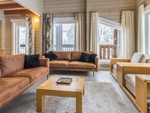 A cozy living room with a brown leather sofa, a wooden coffee table, and a patterned rug. - Uulanlinna b, paritalo by Interhome (Hyrynsalmi)