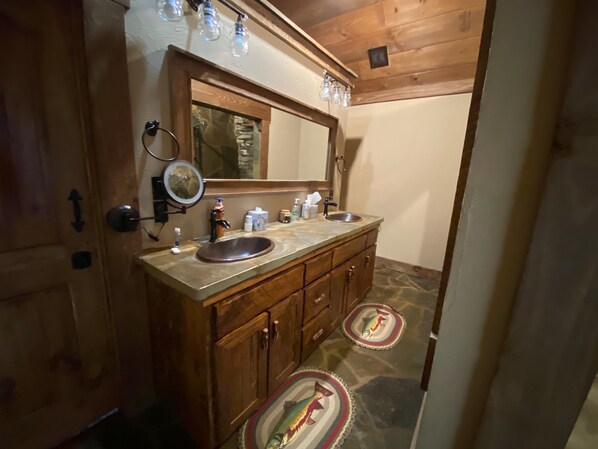 A bathroom with a wooden vanity, double sink, and a mirror above the sink.