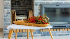 A fireplace with a stone wall, a television, and a table with a floral arrangement. - Vacation Home Sestel with Sea View, Pool, Balcony, Garden & Terrace (Capdepera)