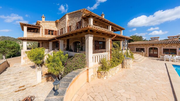 Une villa en pierre dotée d’une piscine, d’un espace salon extérieur et d’un escalier menant à l’entrée.