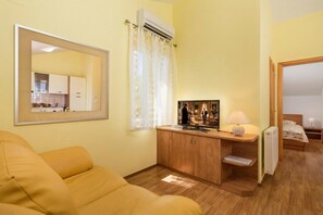 Une pièce comprenant un canapé, une armoire en bois, un miroir, un cadre photo, une lampe et un lit.