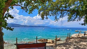 A bench overlooking a coastal area with clear blue waters and distant mountains. - Pool Suite Glavotok at Krk Island, Krk, Croatia (Krk)