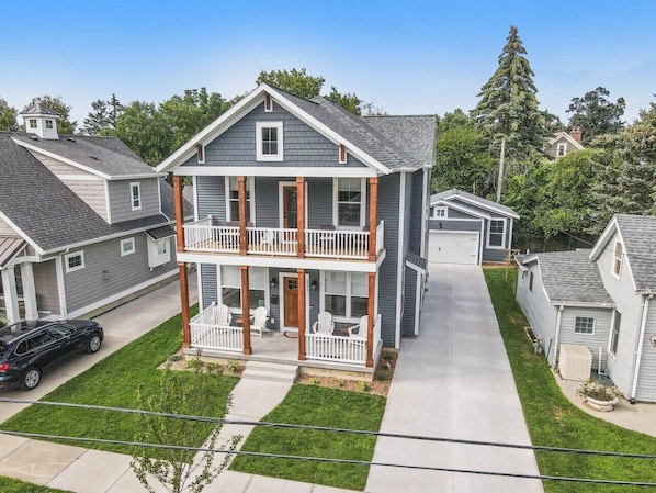 A two-story residential building with a balcony on the second floor, a front porch, and a driveway.
