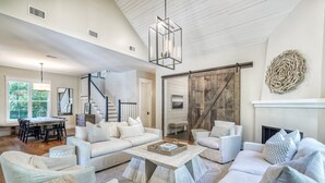 A spacious living room with a large white sofa set, a wooden coffee table, and a fireplace. - Luxury 2-Story Home | 2-min to pool | 8-min to the beach | 1-mile from Seaside (Seagrove Beach)