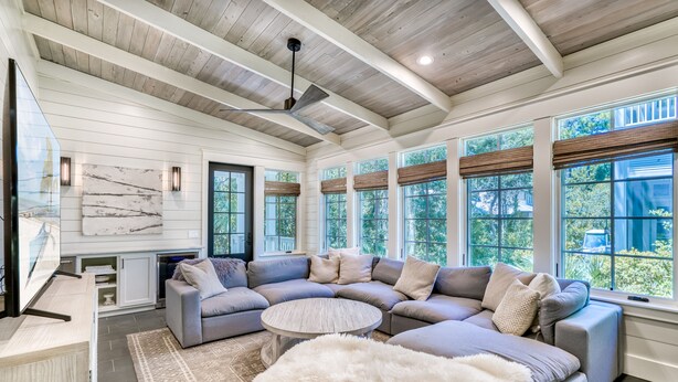 A spacious living room with a large sectional sofa, a round coffee table, and a ceiling fan. - Luxury 2-Story Home | 2-min to pool | 8-min to the beach | 1-mile from Seaside (Seagrove Beach)