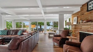 A spacious living area with a leather sofa, armchairs, and a fireplace.