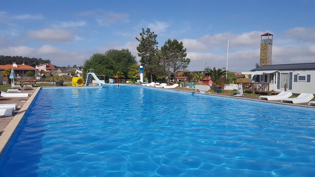A swimming pool with a slide and a lifeguard tower.
