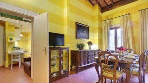 Un coin repas avec une table dressée pour quatre personnes, un téléviseur fixé au mur et un meuble avec des portes en verre.