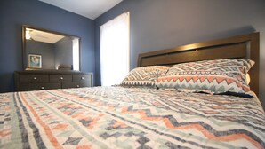 A bedroom with a bed, a dresser, a mirror, and a window with curtains. - Safe, Clean & Spacious, Great for Families (Niagara Falls)