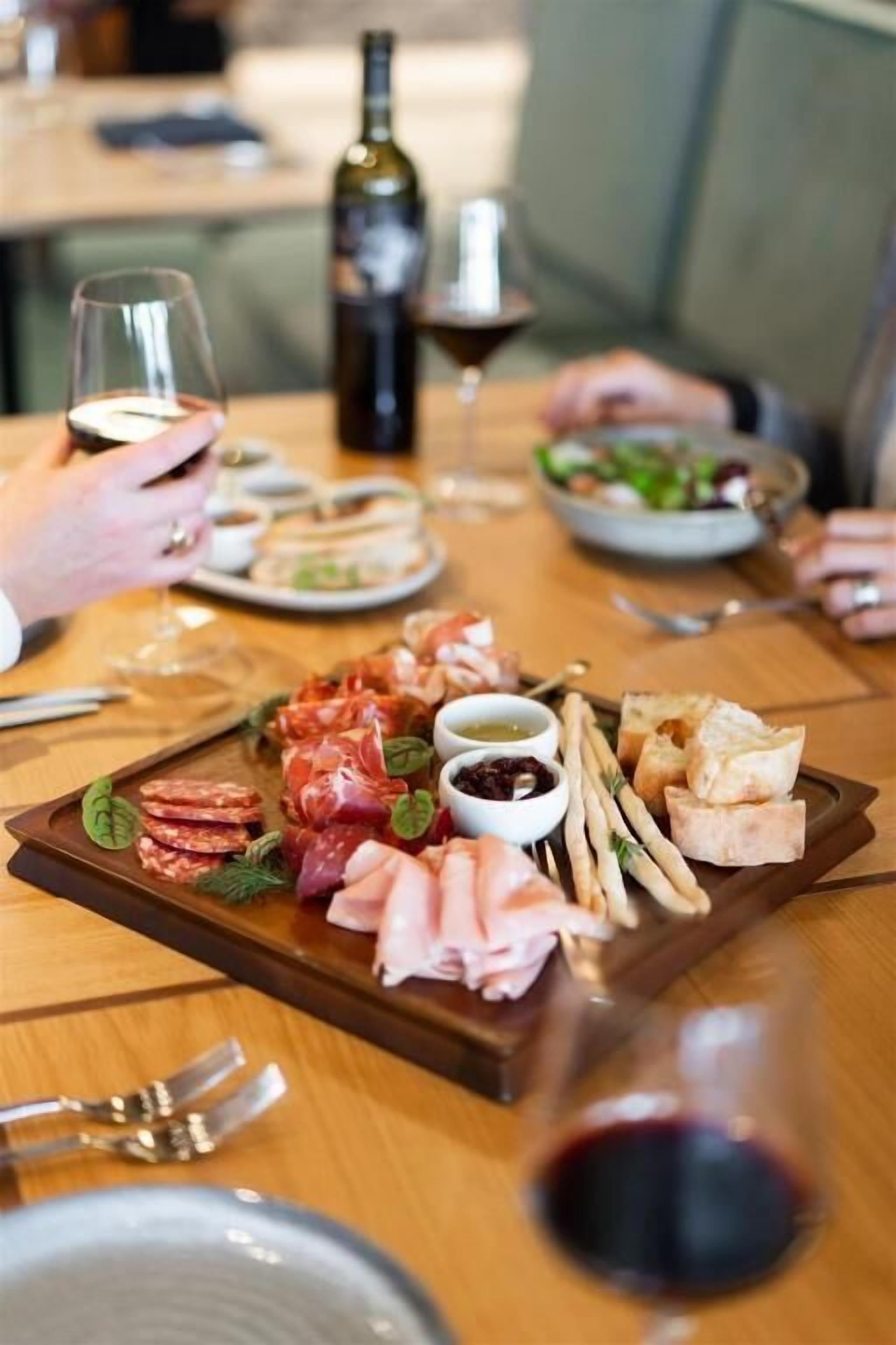 A dining table with a charcuterie board, wine glasses, and a bottle of wine.