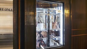 Een koelvitrine met verschillende etenswaren, een deur met een bordje en een gepolijste vloer.