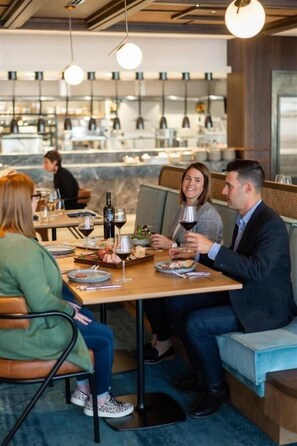 A restaurant with a wooden table, chairs, and hanging lights. - The Gem Hotel (Griffith)