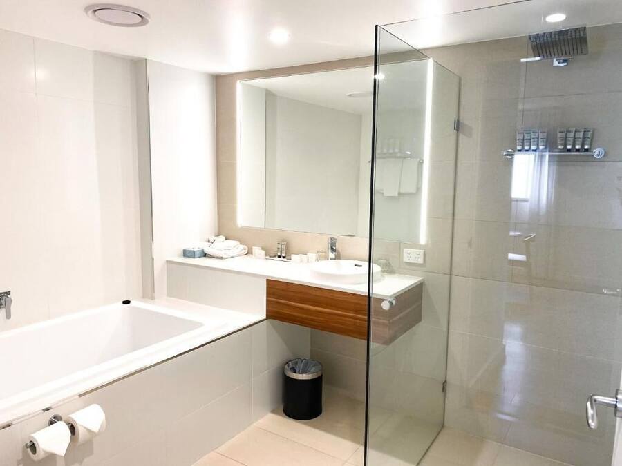A modern bathroom with a glass-enclosed shower, a white sink, and a large mirror.