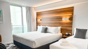 Een hotelkamer met twee bedden, een modern hoofdeinde, een vloer met patroon en uitzicht door het raam.