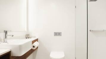 Un baño moderno con un lavamanos, espejo y retrete blancos.