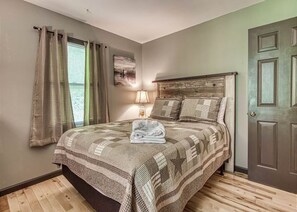 Ein Schlafzimmer mit Bett, Vorhängen, Lampe und Tür.