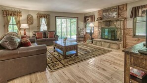 Un salon spacieux doté d’un plancher en bois, d’un canapé, d’une table basse et d’une cheminée.