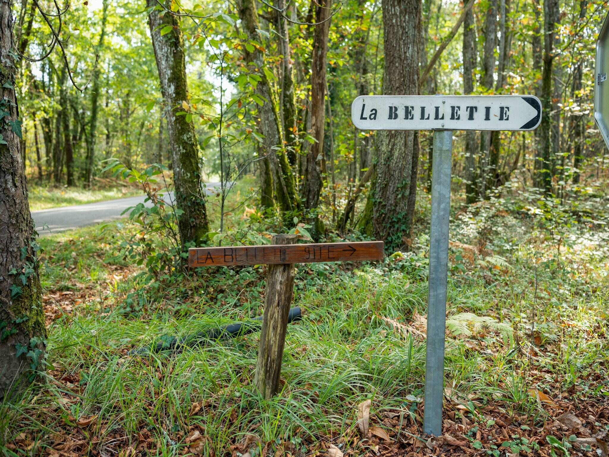 A directional signpost in a forested area with a sign pointing to 'La BELLETIE'.