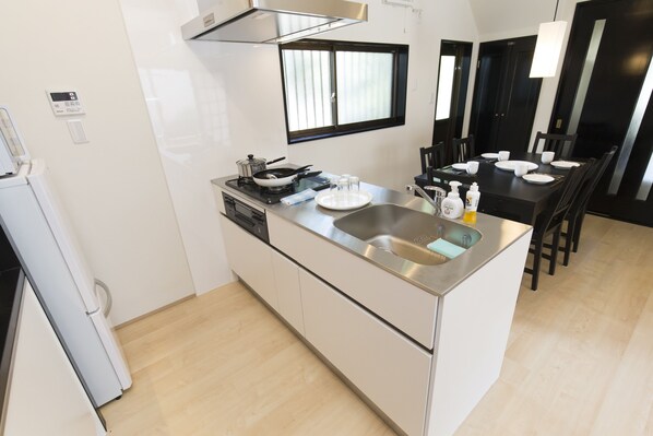 A compact kitchen with a built-in stove, a sink, and a dining area with chairs and a table. - Temari (Hakone)
