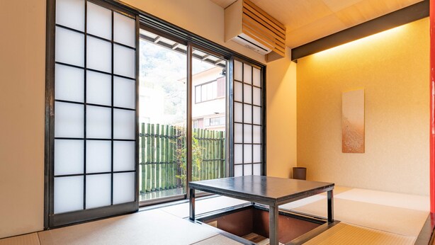Una habitació amb tatamis, una porta corredissa de shoji, una taula baixa i vista cap a l'exterior.