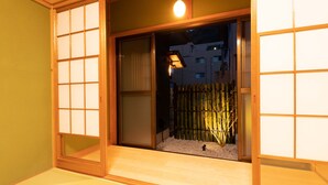 Una habitació japonesa tradicional amb portes corredisses, un jardí interior petit i un lluminari penjant.