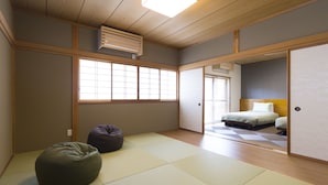 Habitació japonesa tradicional amb sòls de tatami, un llit futó, un seient de borra i portes corredisses.