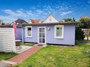 Une maison de plain-pied avec une porte d’entrée, deux fenêtres et un petit porche.