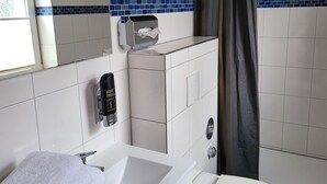Casa de banho com lavatório branco, sanita, secador de mãos e um porta-toalhas.