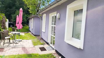Un edificio residencial con patio, mobiliario exterior y un automóvil estacionado cerca.