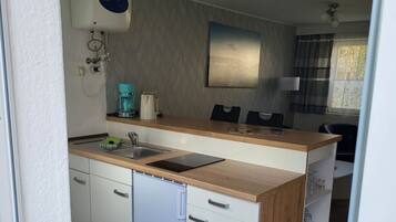 Una cocina compacta con lavavajillas integrado, cafetera y microondas.