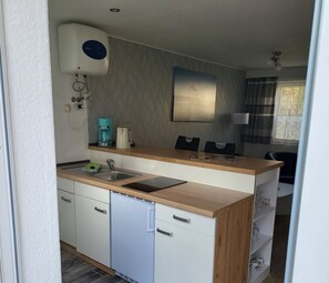 A compact kitchen with a built-in dishwasher, a coffee maker, and a microwave.