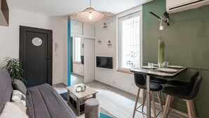Ein modernes Wohnzimmer mit grauem Sofa, einem kleinen Couchtisch und einem Essbereich mit Tisch und Stühlen.